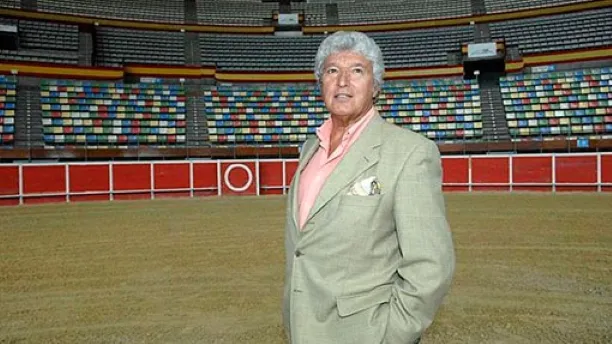 Retrato editorial de Luis Álvarez en una plaza de toros, rodeado por elementos discretos que recuerdan su trayectoria como apoderado y empresario.