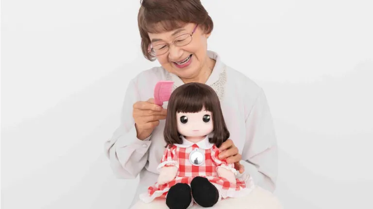 Una muñeca de apariencia realista frente a una niña, con una sutil interfaz digital reflejada en sus ojos. Estética tecnológica, inquietante y editorial, sin caer en el terror ni presentar la inteligencia artificial como una amenaza inevitable.